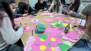 Uczniowie w sali lekcyjnej wycinają kwiaty i umieszczają na nich napisy