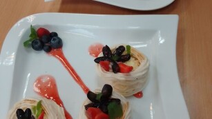 6 porcji deseru mini bezy Pavlovej na dwóch talerzykach ozdobione owocami