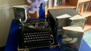 stara maszyna do pisania i książki na stoliku z bukietem kwiatów